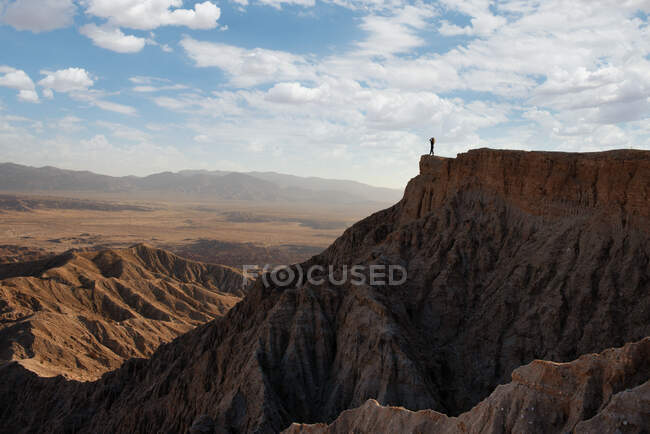 Mujer de pie en la montaña mirando las tierras baldías vista de la montaña, Anza Borrego Desert State Park, California, EE.UU. - foto de stock