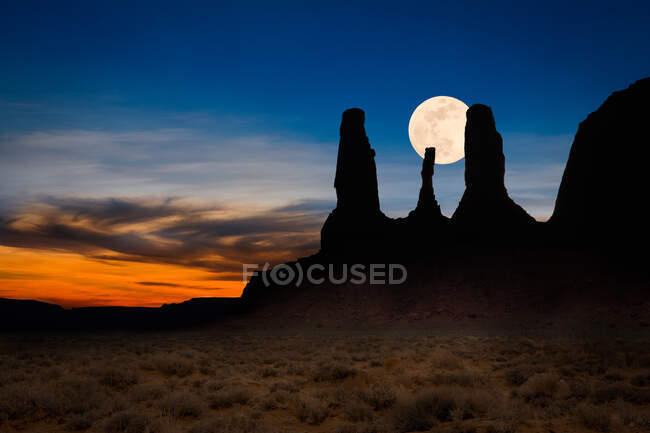 Luna che sorge dietro una sagoma di Tre Sorelle, Monument Valley, Arizona, USA — Foto stock