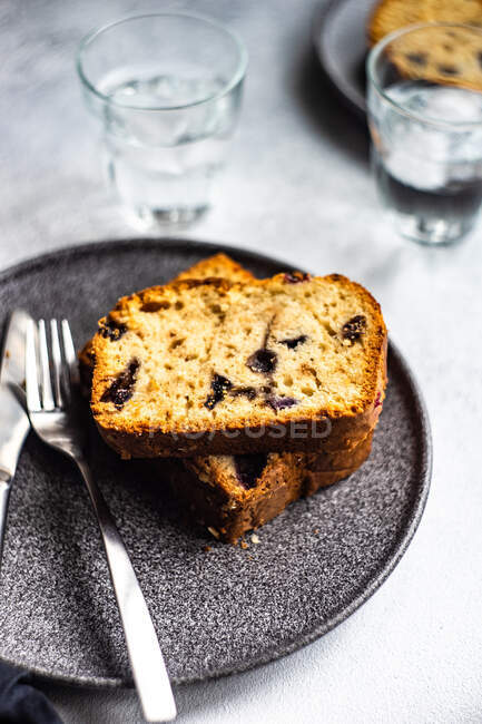 Two servings of blueberry cake with glasses of water on a table — Stock Photo