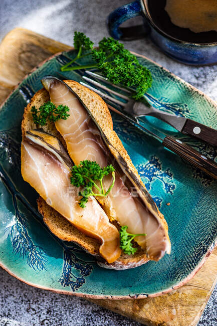 Slice of bread with smoked sturgeon and a cup of black coffee — Stock Photo
