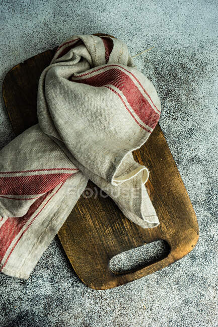 Overhead view of a tea towel on a wooden chopping board on a table — Stock Photo