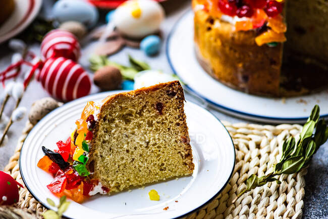 Tranche de gâteau de Pâques avec des fruits glacés sur une table avec des décorations de Pâques — Photo de stock