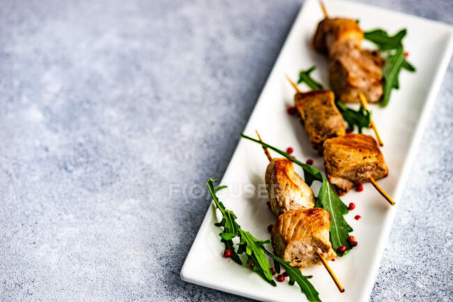 Barbecue pork skewers with rocket leaves — Stock Photo