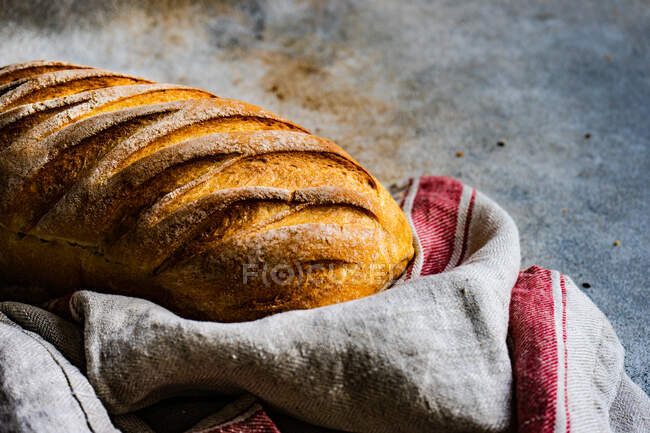 Close-up of a loaf of bread and a tea towel on a table — Stock Photo