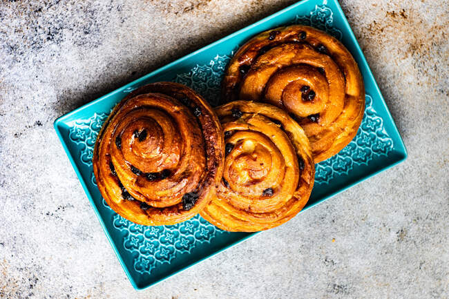 Overhead view of three sweet buns with raisins on a plate — Stock Photo
