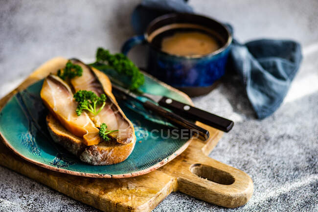 Scheibe Brot mit geräuchertem Stör und einer Tasse schwarzem Kaffee — Stockfoto