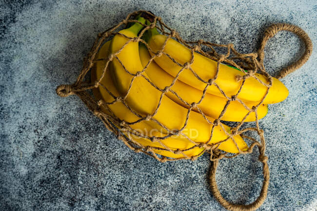 Bunch of bananas in a reusable eco mesh bag on a table — Stock Photo