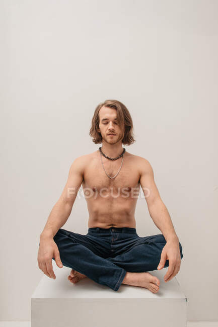 Портрет человека без рубашки, сидящего со скрещенными ногами на коробке — стоковое фото
