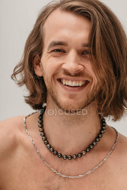 Портрет улыбающегося красивого мужчины без рубашки в ожерельях — стоковое фото