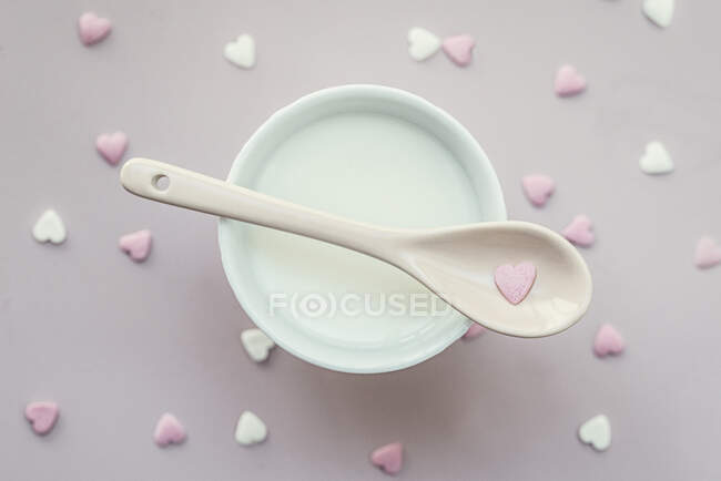 Vista aérea de una taza de leche con decoraciones en forma de corazón espolvorear sobre la mesa - foto de stock