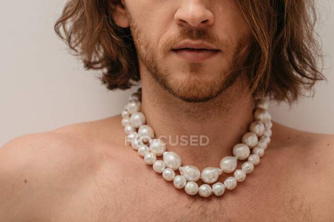 Retrato de um belo homem sem camisa usando colares de pérolas — Fotografia de Stock