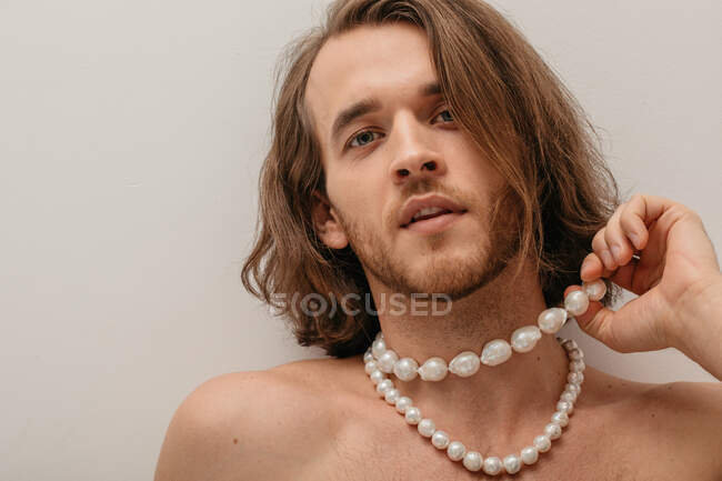 Retrato de un hombre guapo sin camisa con collares de perlas - foto de stock
