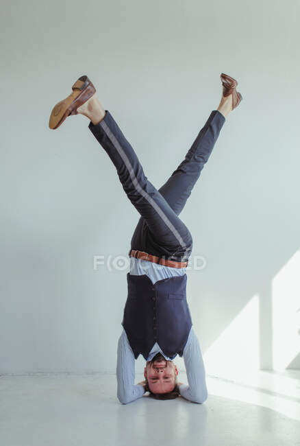 Человек стоит на голове со скрещенными ногами — стоковое фото