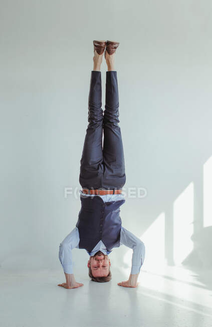 Man standing on head and hands in studio — Stock Photo