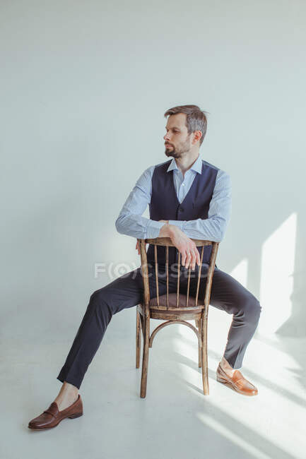 Mann mit grauen Haaren posiert auf Stuhl im Studio — Stockfoto