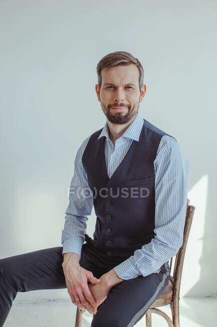 Homem vestindo desgaste formal sentado na cadeira e sorrindo para a câmera — Fotografia de Stock