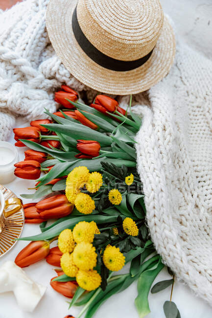 Concetto di vacanza estiva. sacchetto di paglia con fiori, tulipani e altri accessori su uno sfondo di legno grigio. — Foto stock
