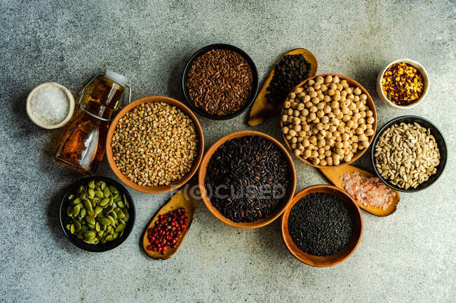Grano crudo y variedad de semillas en un tazón sobre fondo de hormigón - foto de stock
