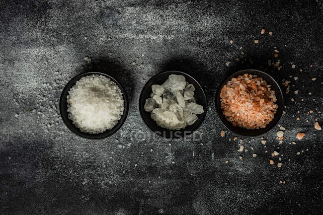 Cooking concept with variety of salt seasoning on dark concrete background — Stock Photo