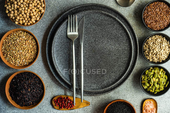 Place setting with variety of bowls full of grain and seeds on concrete background — Stock Photo