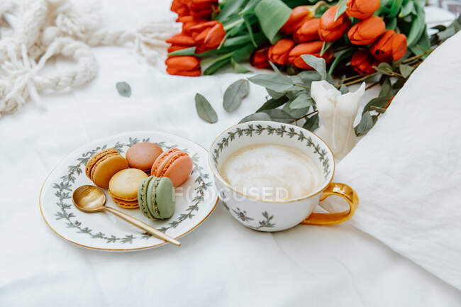 Tasse Kaffee und Makronen mit roten Tulpenblüten am Tisch — Stockfoto