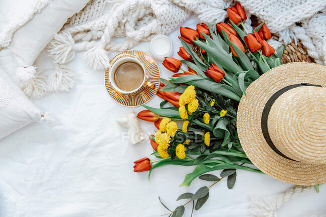Cup of coffee with flowers and straw hat — Stock Photo
