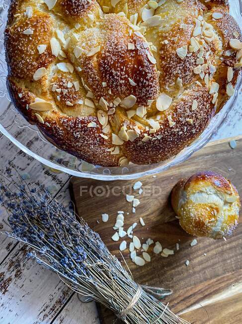 Болгарський Великодній хліб з мигдалями на скляному торті біля купки сушеної лаванди на дерев'яній дошці для рубації. — стокове фото