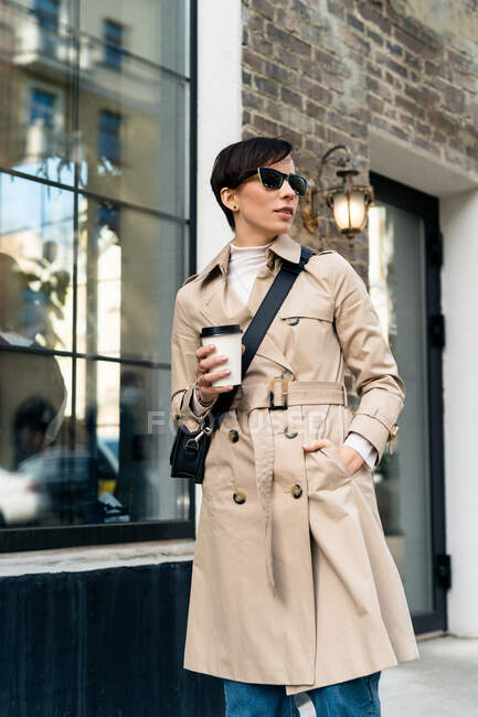 Frau steht auf der Straße und hält Kaffee zum Mitnehmen in einem Einwegbecher — Stockfoto