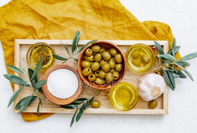 Wooden tray of bowls with olive oil and olives with branches on white background — Stock Photo