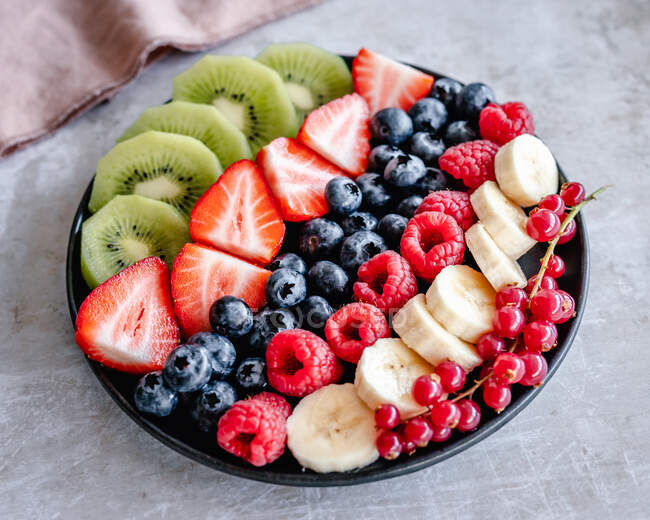 Bandeja de fruta fresca con fresa, frambuesa, plátano, arándano, kiwi y grosella roja - foto de stock