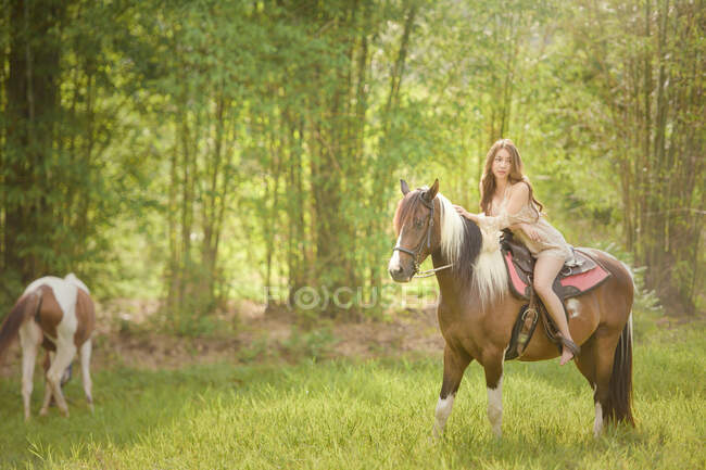 Босоногая женщина верхом на лошади на лугу, Таиланд — стоковое фото