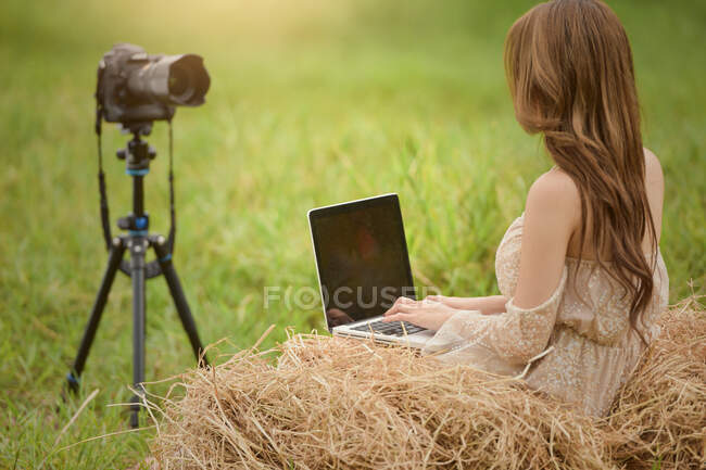 Schöne Frau sitzt auf einer Wiese und filmt im Freien, Thailand — Stockfoto
