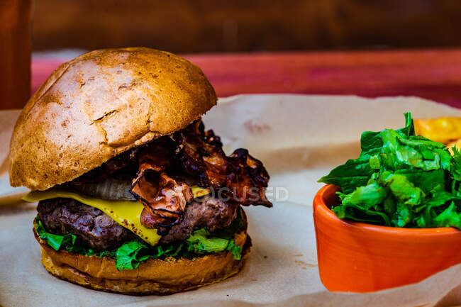 Домашний техасский гамбургер с салатом из бекона и капусты, подаваемый на деревянной доске — стоковое фото