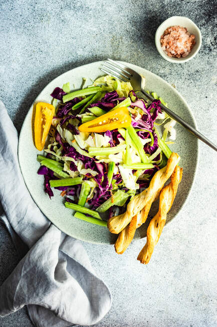 Salade de légumes santé servie dans un bol en pierre avec grissini sur table en béton — Photo de stock