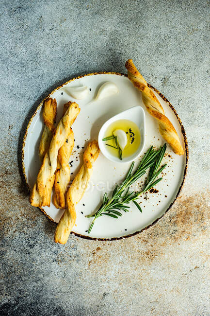 Grissini bastoncini e olio d'oliva con rosmarino fresco servito sul piatto — Foto stock