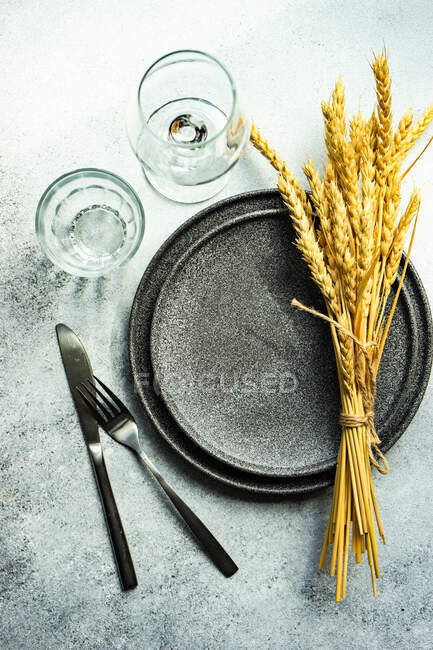 Summer place setting with wheat ears and stoneware on concrete table — Stock Photo