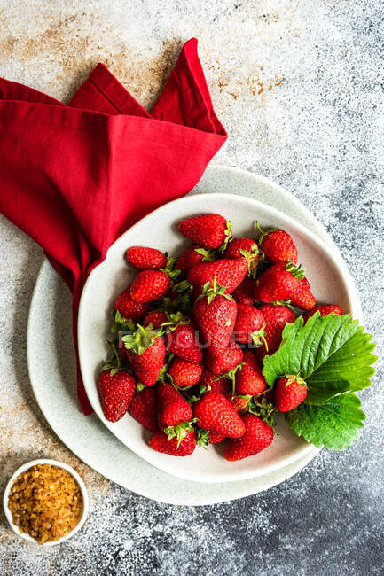 Concepto de alimentación saludable con fresas frescas crudas servidas en un tazón sobre un fondo de hormigón - foto de stock
