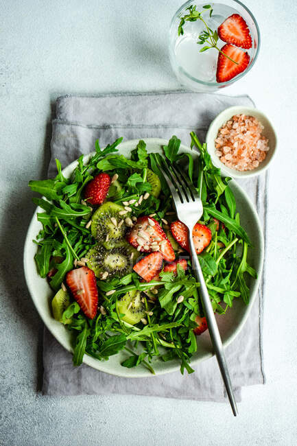 Bol à salade bio avec rucola et fraise sur table en béton — Photo de stock