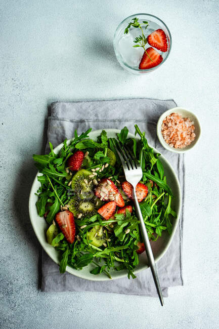 Миска з органічним салатом з руколами та полуницею на бетонному столі — стокове фото
