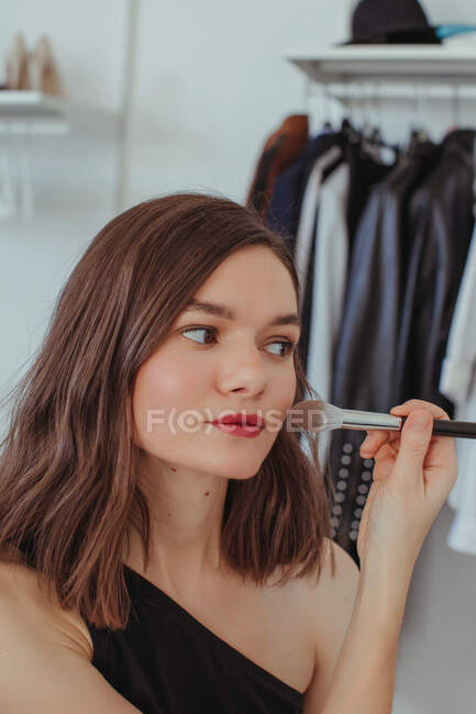 Retrato de uma mulher bonita aplicando blusher e pó de rosto — Fotografia de Stock