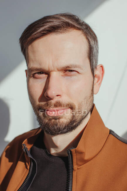Retrato de um homem bonito com uma barba em pé à luz do sol — Fotografia de Stock