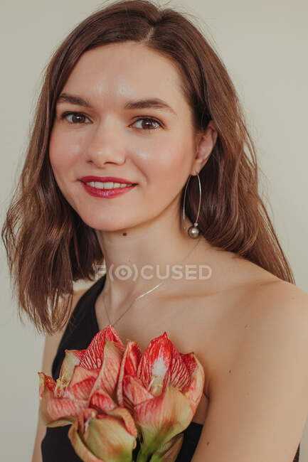 Retrato de uma bela mulher sorridente segurando uma flor amaryllis — Fotografia de Stock