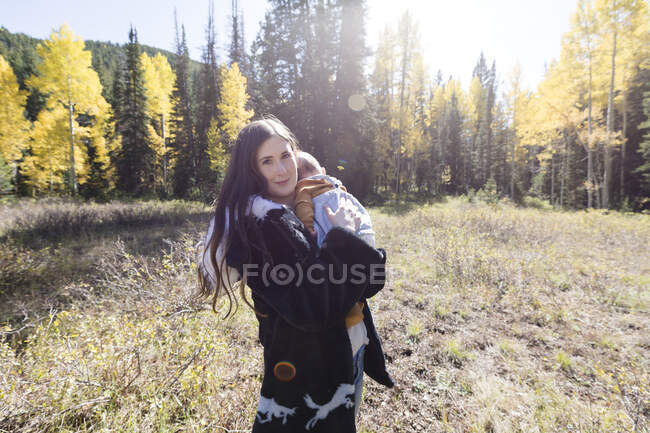 Ritratto di una donna in piedi nella foresta che tiene in braccio la sua bambina, California, USA — Foto stock