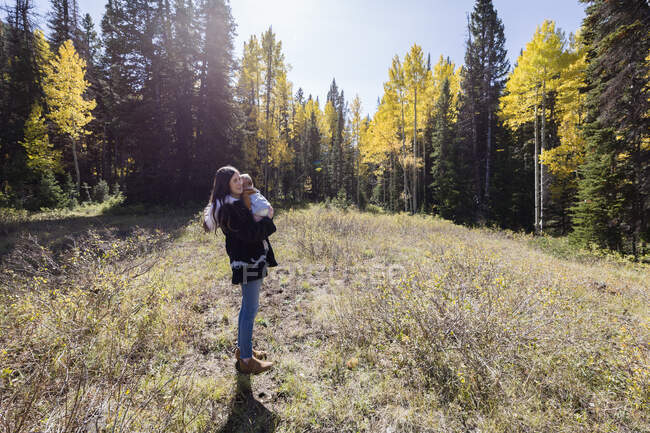Портрет женщины, стоящей в лесу, держащей свою маленькую дочь, Калифорния, США — стоковое фото
