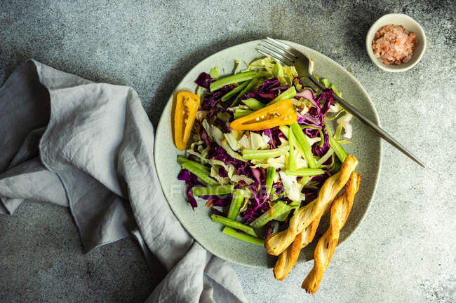 Salade de légumes santé servie dans un bol en pierre avec grissini sur table en béton — Photo de stock