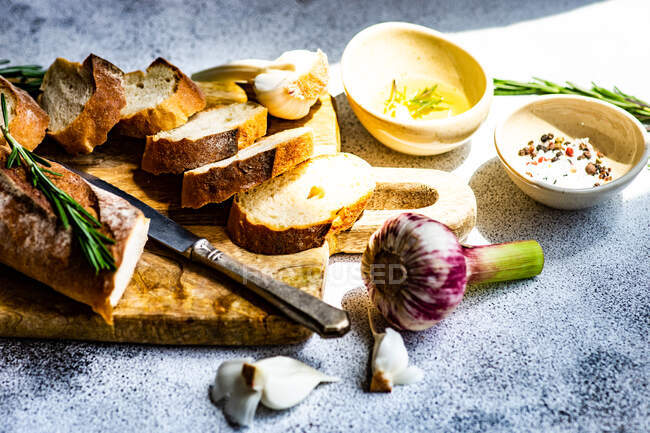 Concepto de comida con rodajas de baguette francesa y aceite de oliva sobre fondo de hormigón - foto de stock