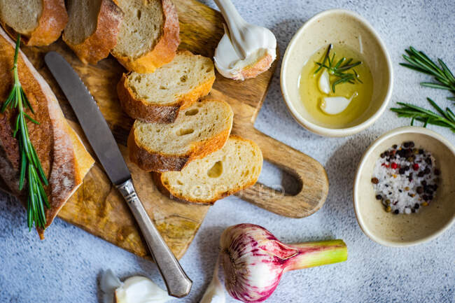 Concepto de comida con rodajas de baguette francesa y aceite de oliva sobre fondo de hormigón - foto de stock