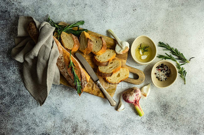 Концепция продуктов питания с ломтиками французского багета и оливкового масла на бетонном фоне — стоковое фото