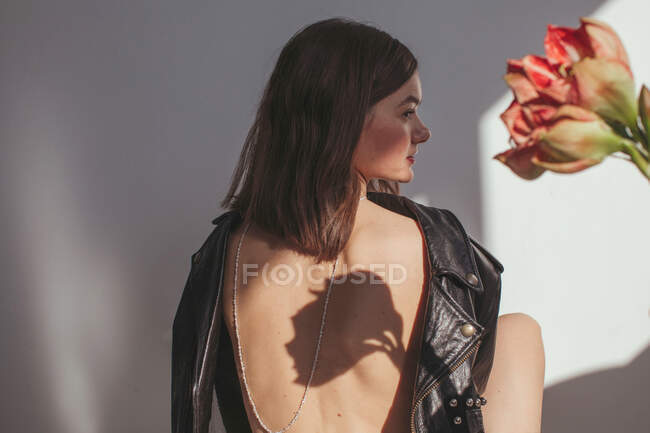 Rückansicht einer Frau, die eine Lederjacke von hinten nach vorne trägt, mit einer Kette auf dem nackten Rücken — Stockfoto
