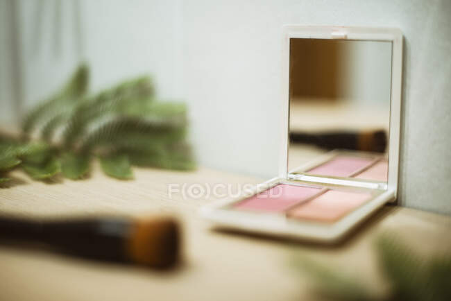 Nahaufnahme einer Kosmetikpalette und eines Make-up-Pinsels auf einem Tisch — Stockfoto
